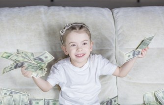  a little girl sitting on a couch holding money