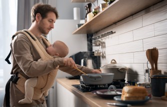 Father cooking while holding baby medium shot