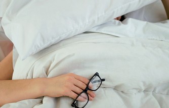 person asleep holding eyeglasses