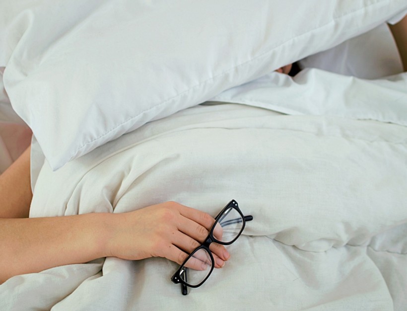 person asleep holding eyeglasses